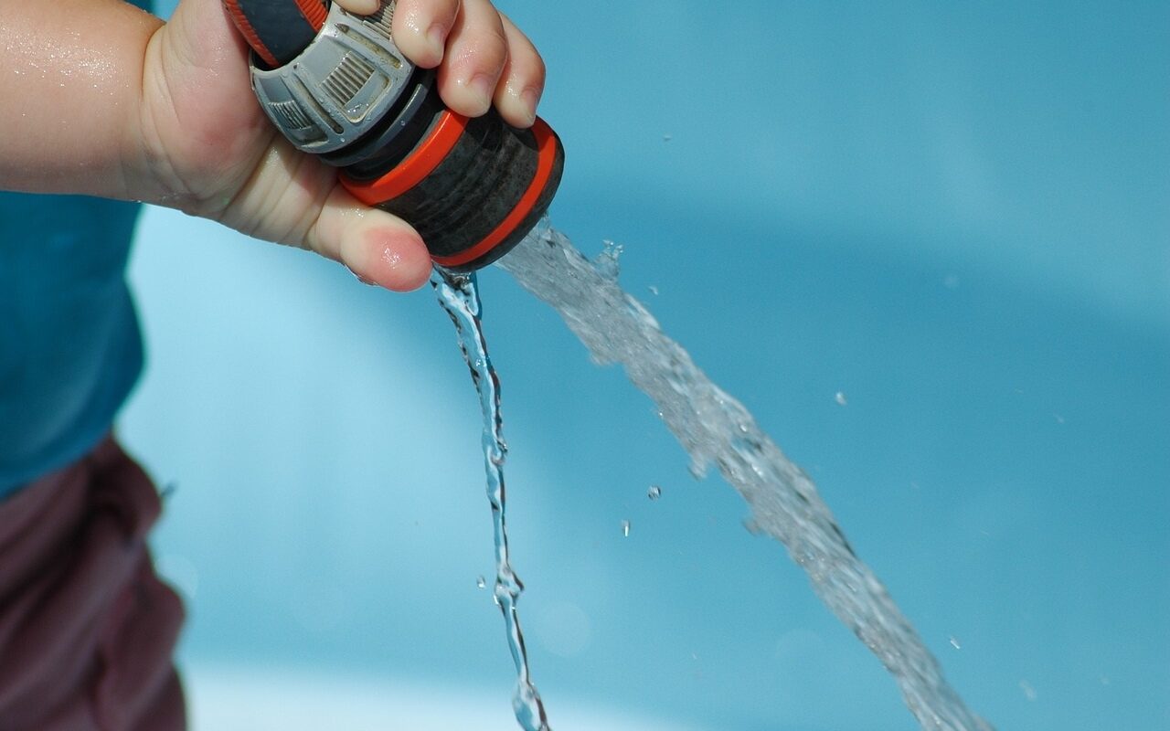 main d'enfant versant de l'eau avec un tuyau d'eau